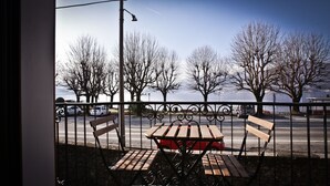 Een balkon met uitzicht op een rivier, banken en een tafel.