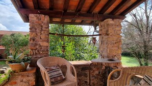 A stone-built outdoor patio with wicker furniture, a rustic table, and hanging planters.