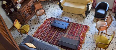A living room with a sofa, chairs, a TV, a wooden cabinet, and a patterned rug.