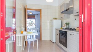 A compact kitchen with white cabinets, a gas stove, a refrigerator, and a dining area with a table and chairs. - Holiday house in Torre Lapillo beach (TL23) (Torre Lapillo)