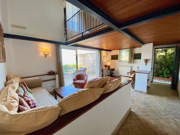 A cozy living room with a sofa, a red armchair, and a dining table. There is a staircase leading to an upper level. - Spacious house in Resort. (Taormina)