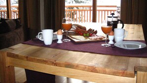 Une table de petit-déjeuner avec des œufs, du bacon et des toasts, disposés sur une table en bois surmontée d’une nappe violette.
