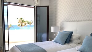 Een hotelkamer met twee bedden, uitzicht op de oceaan en een kamer met een patroon op de muur.