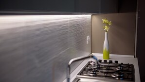 A kitchen with a stove, a vase with flowers, and a textured wall. - Apartment Standard Suite  4 (Vasto)