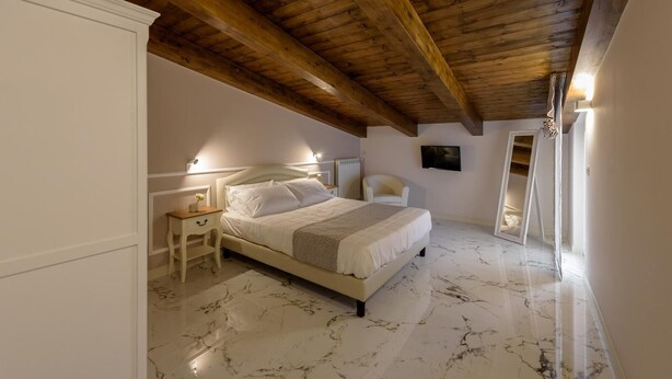 A bedroom with a bed, nightstands, a chair, a TV, and a wooden ceiling. - Apartment Standard Suite  4 (Vasto)