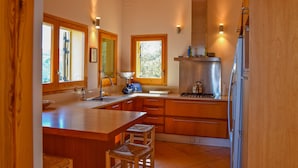 A kitchen with wooden cabinets, a stainless steel refrigerator, and a large window providing natural light. - Villa with stunning sea views and pool in terrace. (Sa Riera)