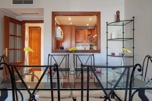 Enjoy meals in this dining area with a glass-top table and four chairs, surrounded by a mirror reflecting the kitchen.