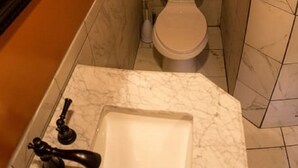 Ein Badezimmer mit Toilette, Marmorwaschbecken und orangefarbenen Wänden.