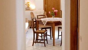 A dining area with a wooden table and chairs, a vase of flowers, and a wooden door in the background. - CONCA "Marechiaro" AMALFI COAST (Conca dei Marini)