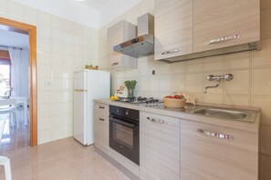 Une cuisine moderne avec un réfrigérateur blanc, une cuisinière, un four et un évier doté d’un robinet en acier inoxydable.