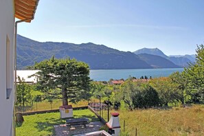 Uitzicht vanaf een balkon op een meer, met bergen op de achtergrond.