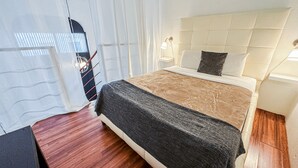 A bedroom with a bed, bedside tables, and a window with curtains. - Loft Aparment Steps From Nightlife, Gladiolas II /Loft + Room /Free WIFI - 2101 (Ponce Pueblo)