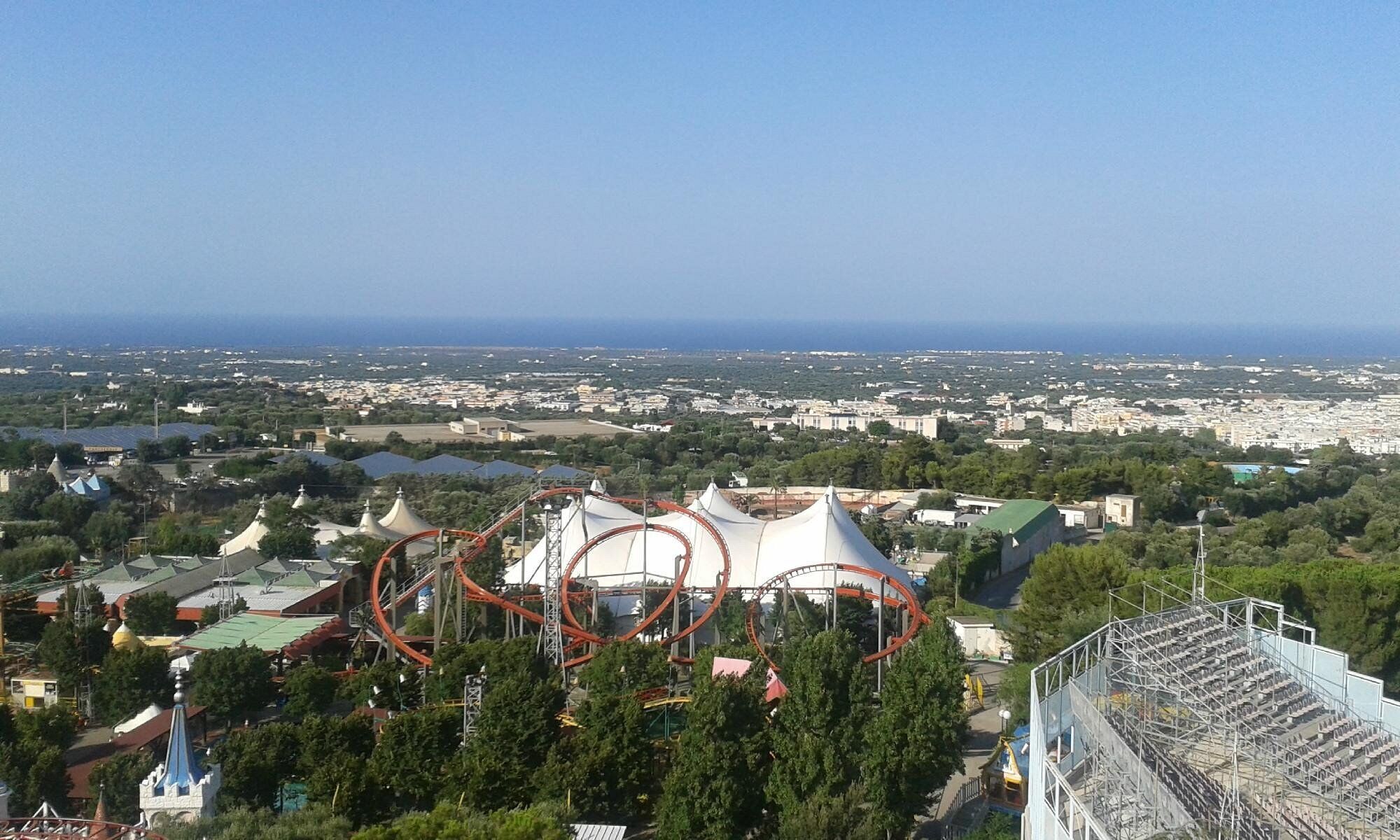 Vista de una ciudad costera con una montaña rusa y un estadio.