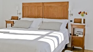 A neatly made bed with a wooden headboard, two bedside tables with lamps, and a small shelf with books.
