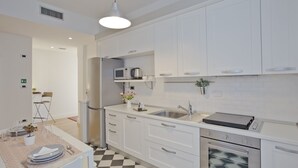 A modern kitchen with white cabinets, a built-in oven, and a microwave.