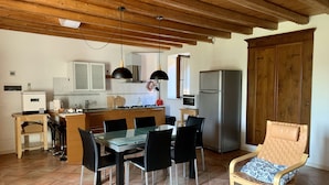A compact kitchen with modern appliances, a dining area with a table and chairs, and a wooden ceiling. - Cozy Apartment for Two on the Hills of Lake Garda (Toscolano Maderno)