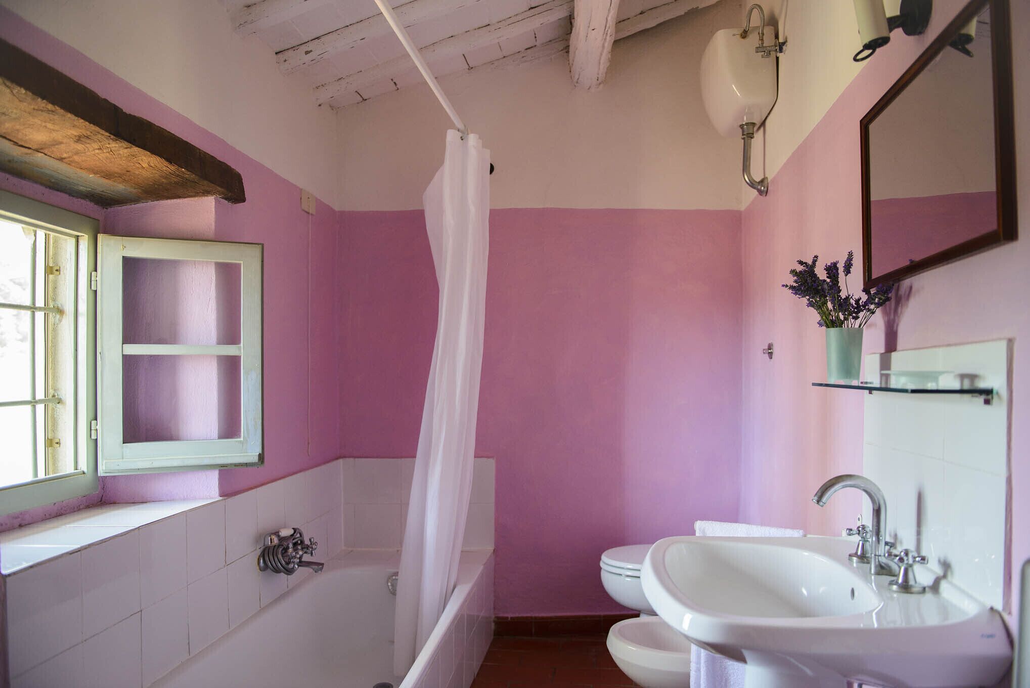 Ein Badezimmer mit einer Badewanne, zwei Waschbecken, einem Fenster mit grünem Rahmen und einem Spiegel.