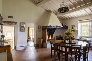 A dining area with a brick fireplace, wooden table, and chairs. - Authentic farmstay for family & friends with Pool, among Vineyards & Olive trees (Bucine)