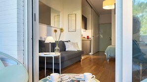 En moderne stue med en sofa, et lille bord med en lampe, samt et spiseområde med en stol og bord.