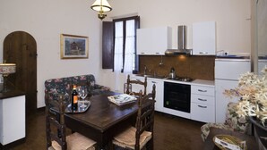 A compact kitchen with white cabinets, a wooden dining table, and a floral sofa. - Farmhouse in the Chianti "La Foresta 1" with swimming pool  (San Leonino)