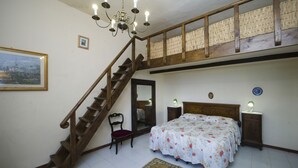 A bedroom with a wooden staircase, a bed with floral bedding, a chair, bedside lamps, and a rug. - Farmhouse in the Chianti "La Foresta 1" with swimming pool  (San Leonino)