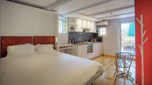 A bedroom with a large bed, a kitchenette, and a dining area with chairs. - THE GARDEN OF THE VILLAGE IN VALBONNE (3 ***): live in-out (Valbonne)