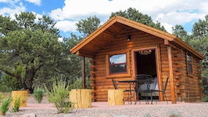 A log cabin with a patio and a table with chairs.