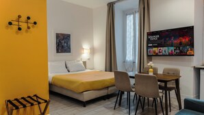 Hotellihuone, jossa on sänky, työpöytä, tuoli ja pieni pöytä.