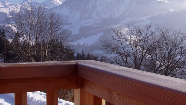 Un paysage de montagne avec des sommets enneigés et des arbres sans feuilles.