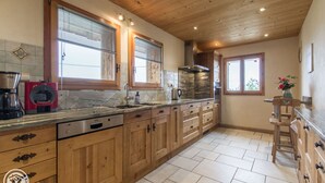 Une cuisine dotée de meubles en bois, d’un lave-vaisselle, d’un plan de travail en granit et d’une fenêtre avec des stores.