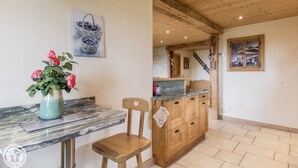 Une cuisine avec des meubles en bois, un plan de travail en marbre et un vase rempli de fleurs.