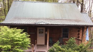 A rustic log cabin with a metal roof, a wooden porch with two rocking chairs, and a sign that reads "Cherokee." -  Cherokee Family Cabin  (Hico)