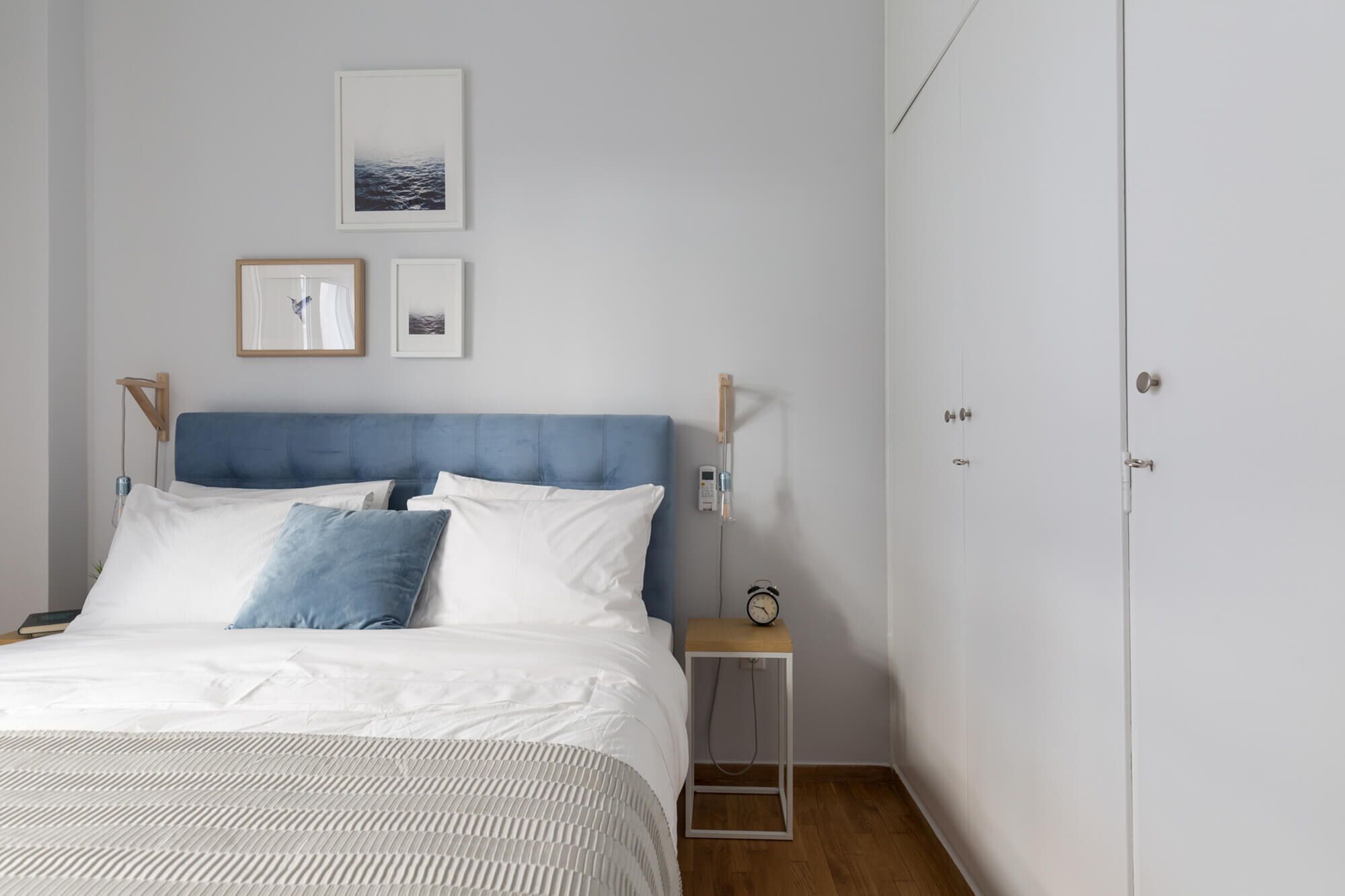 A bedroom with a bed, bedside tables, a wardrobe, and wall-mounted artwork.