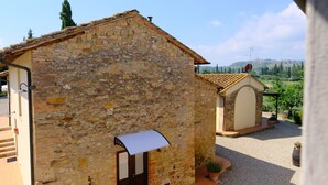 A stone building with a rustic appearance, featuring a small entrance and a gravel courtyard. - Montegonfoli 6 San Gimignano Countryside Apt. with amazing views and pool (san gimignano)
