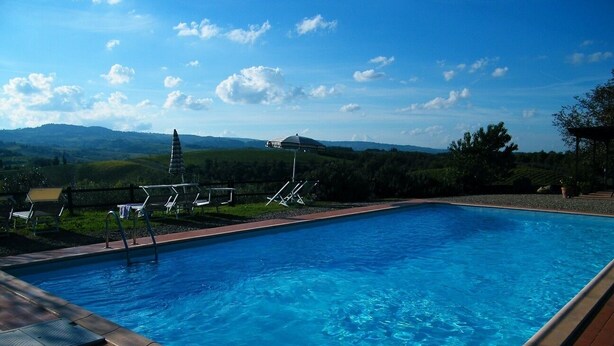 A rectangular swimming pool with clear blue water, surrounded by a wooden deck. - Montegonfoli 6 San Gimignano Countryside Apt. with amazing views and pool (san gimignano)