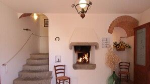 A stone staircase leading to a room with a fireplace, a wooden chair, and a vase with dried flowers. - Montegonfoli 6 San Gimignano Countryside Apt. with amazing views and pool (san gimignano)