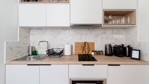 A modern kitchen with white cabinets, a wooden countertop, a built-in oven, and a coffee machine. - Classy & Charming 1BD Apartment in Kolonaki (Athens)