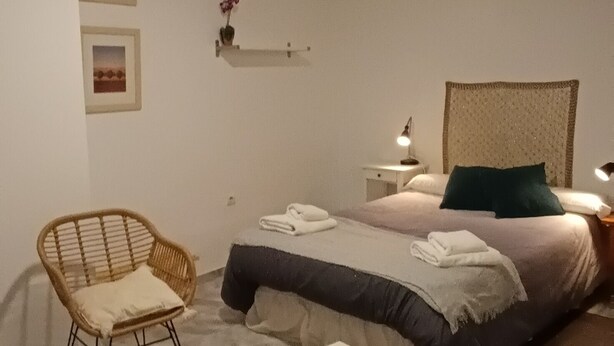 A bedroom with a bed, a chair, a table, a ceiling fan, and wall-mounted shelves. - Quiet in the historic center of Malaga (Málaga)