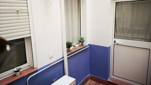 A narrow corridor with a window, a potted plant, and a door with a screen. - Quiet in the historic center of Malaga (Málaga)