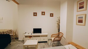 A small, well-lit room with a white desk, a television, a chair, a sofa, and a bed. There are three framed pictures on the wall. - Quiet in the historic center of Malaga (Málaga)