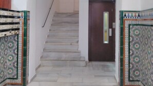 A staircase with a decorative metal railing, a wooden door at the bottom, and patterned floor tiles. - Quiet in the historic center of Malaga (Málaga)