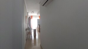 Un couloir étroit avec un ventilateur de plafond et un appareil de climatisation fixé au mur.