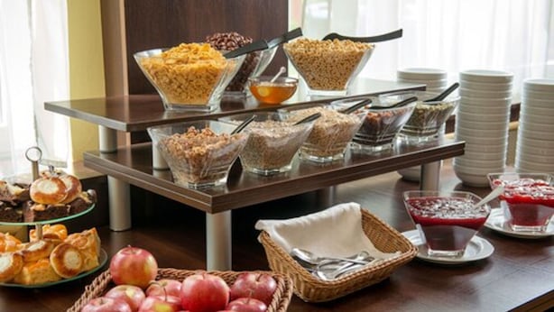 A buffet setup with various food items and a fruit basket. - Hotel Krakus (Kraków)