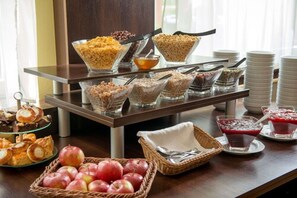 A buffet setup with various food items and a fruit basket. - Hotel Krakus (Kraków)