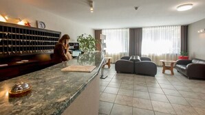 A hotel lobby with a reception desk, seating area, and large windows. - Hotel Krakus (Kraków)