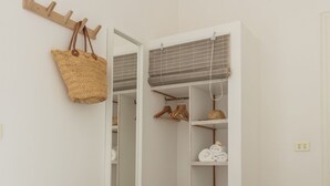 Vestidor con repisas abiertas, un cesto colgante y un perchero de madera.