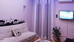 Een moderne woonkamer met een bank, een salontafel en een aan de muur bevestigde televisie.