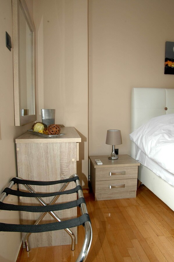 A hotel room with a bed, bedside table, lamp, and a small wooden nightstand. - Enjoy the historical city of ancient and modern Athens staying in the unique. (Athina)