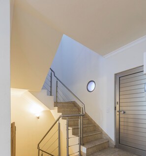 Una escalera con barandilla de metal que lleva a una puerta.