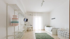 Een slaapkamer met een bed, bureau, stoel, televisie en kledingkast.
